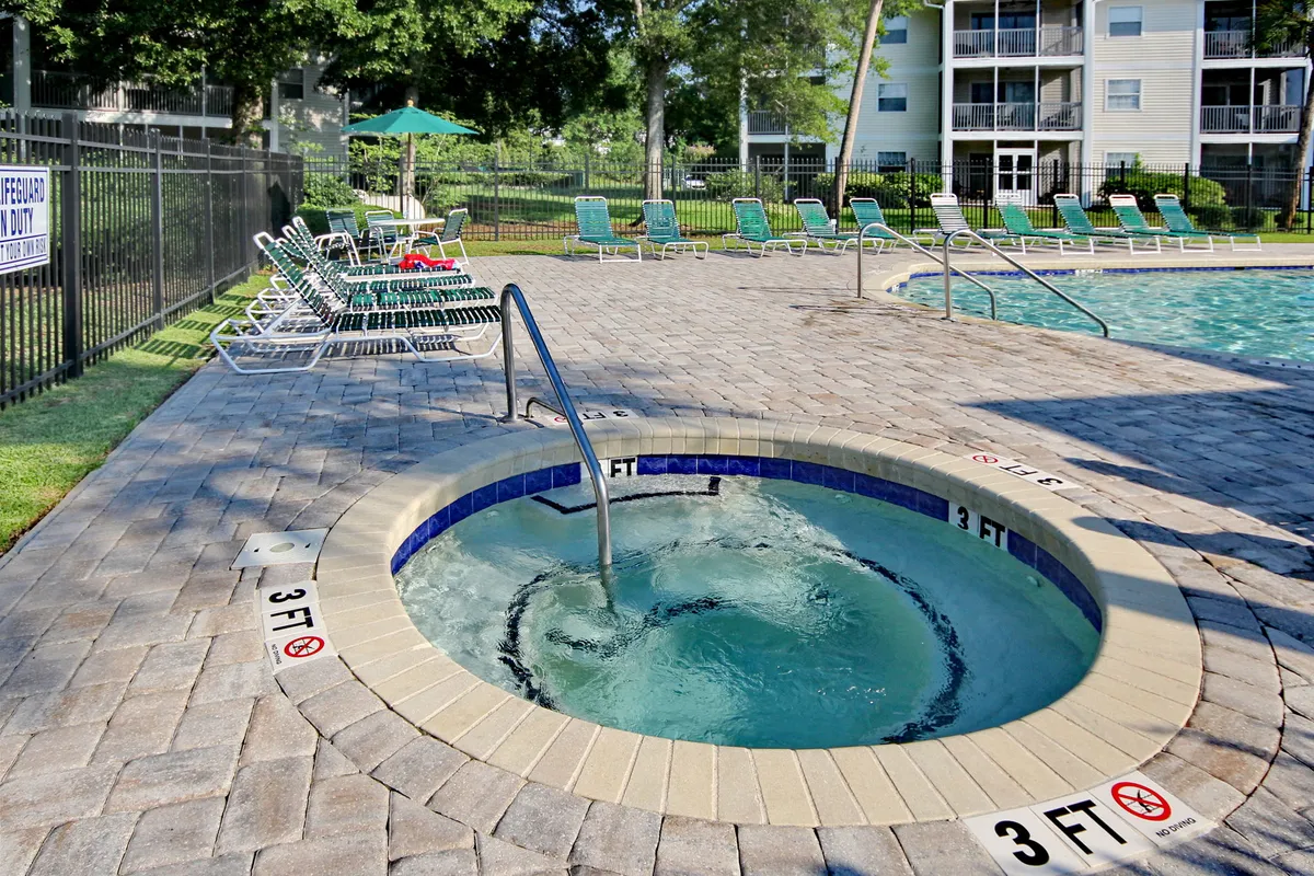 An inviting outdoor space featuring a hot tub and swimming pool surrounded by lounge chairs and vibrant greenery. The setup exudes relaxation and resort-style amenities, perfect for unwinding after a day on the golf course.