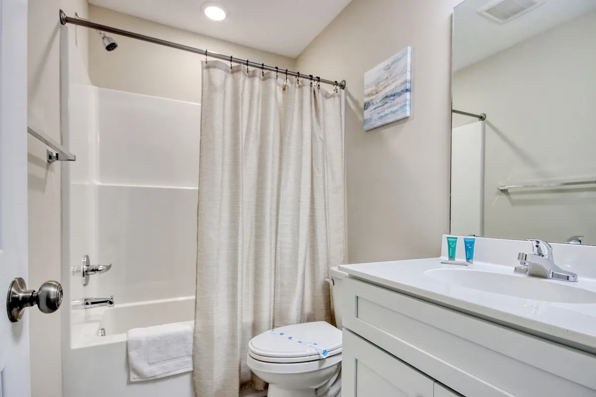 A modern bathroom with a soaking bathtub, large vanity, mirror, and tasteful artwork. The vanity is neatly arranged with toiletries, and the overall space radiates a sense of calm and relaxation.