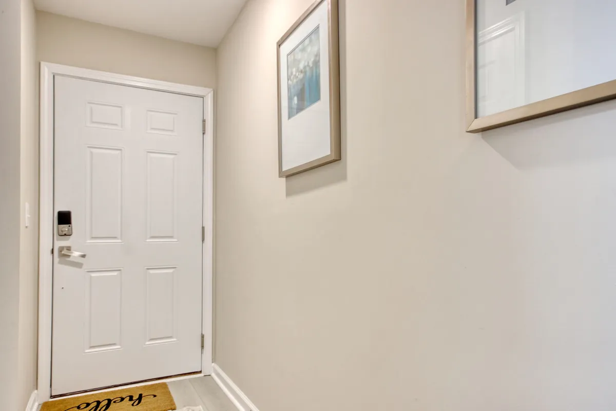 This image captures the condo's front door with decorative wall art and a welcome mat. The scene is warm and inviting, setting a positive first impression that hints at the beginning of an adventure or a relaxing escape. The space feels open and ready for guests to enter or head out for local exploration.