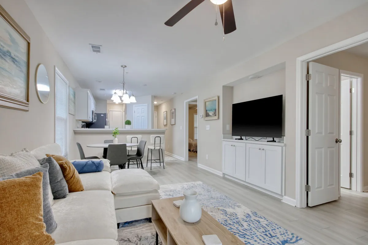 A cozy living space featuring a plush sofa, modern entertainment center with a television, dining table, and decorative wall art. The setting is ideal for entertaining, movie nights, or quiet evenings with loved ones, highlighting the home’s inviting atmosphere.
